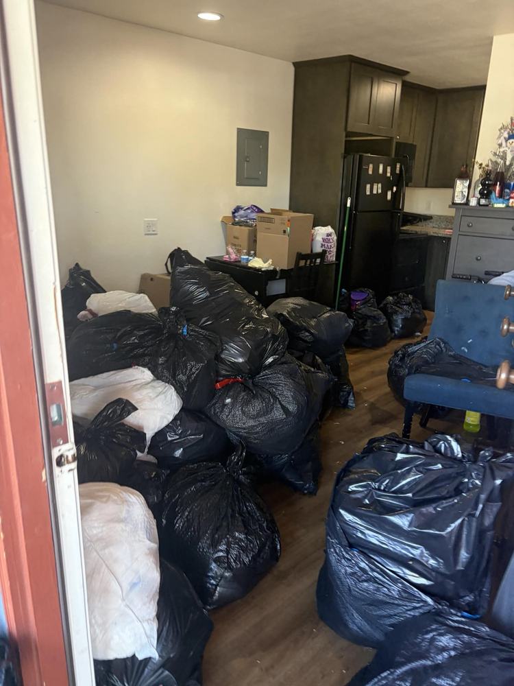 A rental unit with the floor covered end to end in black rubbish bags and boxes